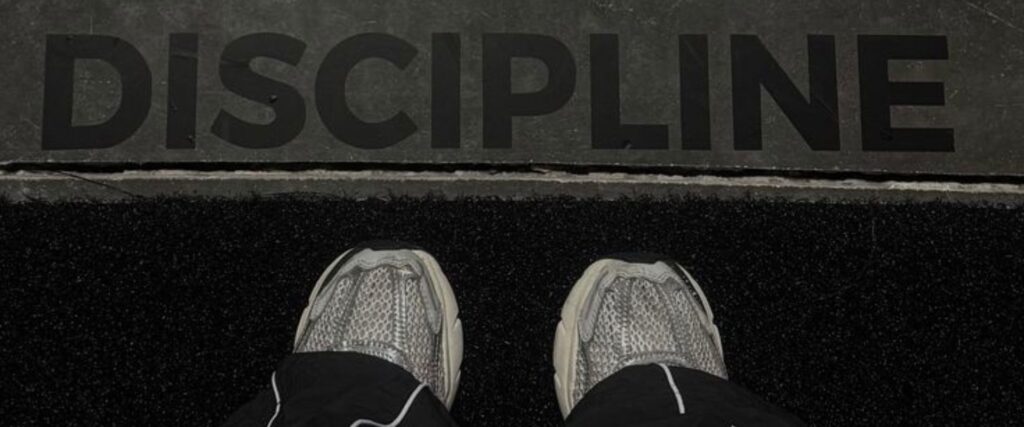 Chaussures de sport devant le mot "Discipline", symbole d'une routine sportive durable.
